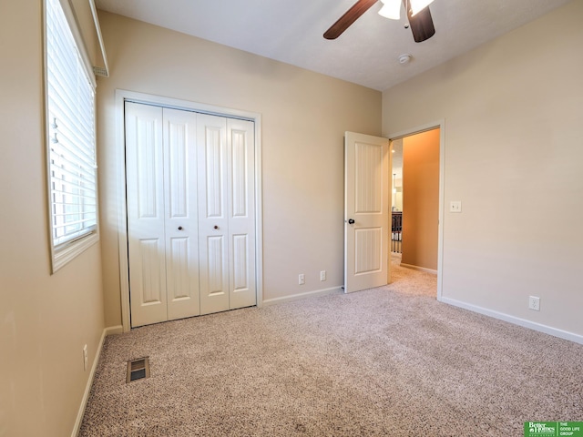 unfurnished bedroom featuring a ceiling fan, visible vents, baseboards, a closet, and carpet