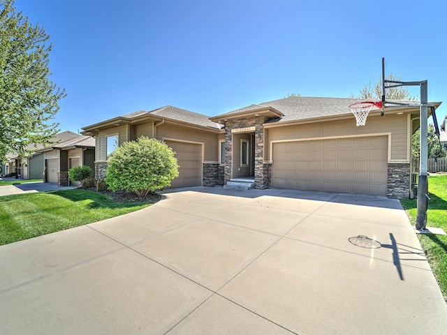 prairie-style house featuring a garage, concrete driveway, a front yard, and stone siding