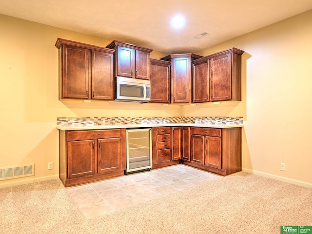kitchen featuring visible vents, light countertops, wine cooler, and stainless steel microwave