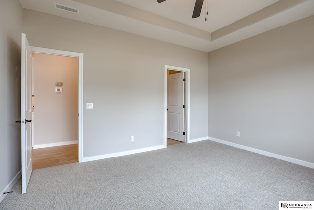 carpeted empty room with visible vents, a ceiling fan, and baseboards