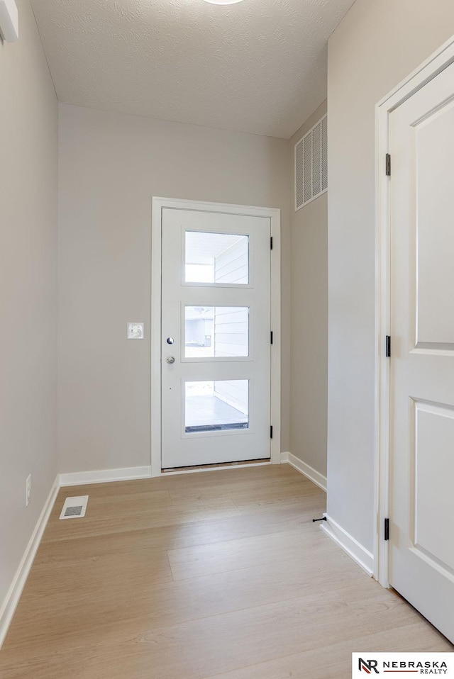 doorway to outside featuring baseboards, visible vents, and light wood-style floors