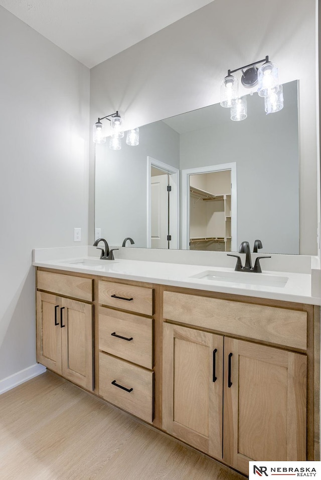 full bath featuring double vanity, baseboards, a sink, and wood finished floors