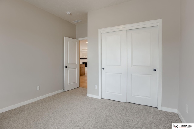 unfurnished bedroom with baseboards, light colored carpet, and a closet