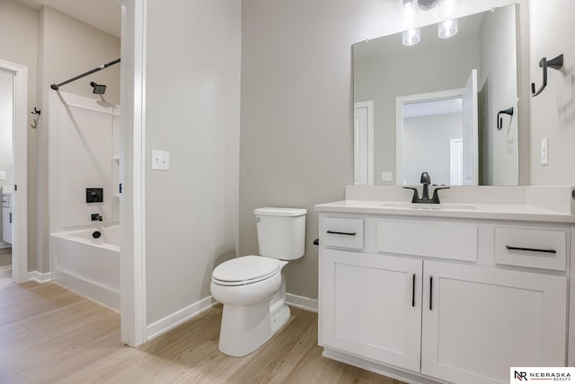 bathroom with vanity, wood finished floors, toilet, baseboards, and shower / tub combination