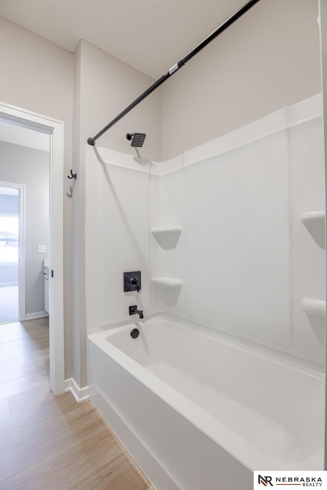 full bath featuring shower / bath combination, baseboards, and wood finished floors