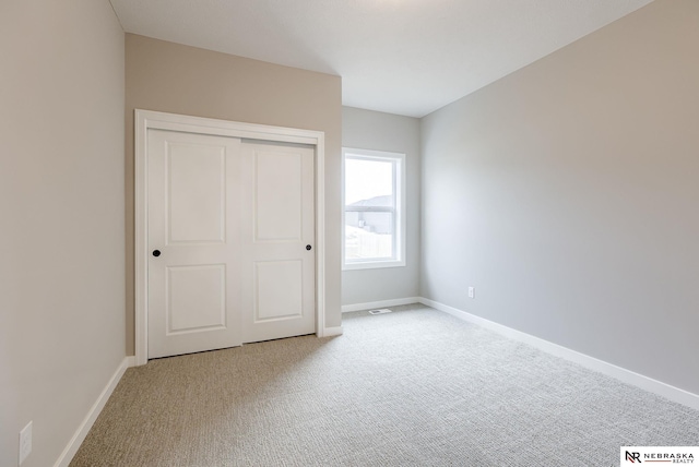 unfurnished bedroom featuring a closet, baseboards, carpet flooring, and visible vents