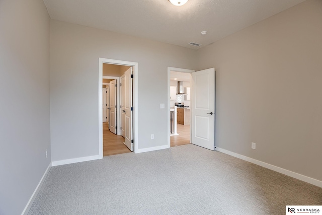 unfurnished bedroom featuring baseboards, visible vents, and light carpet