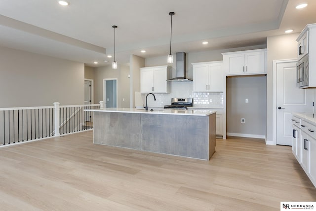 kitchen featuring decorative backsplash, light wood-style floors, wall chimney range hood, recessed lighting, and appliances with stainless steel finishes