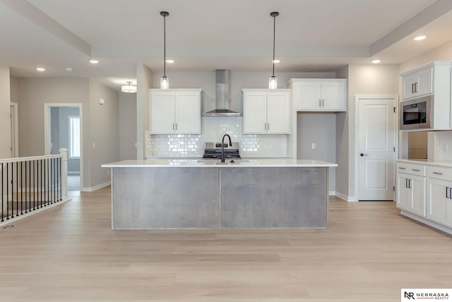 kitchen featuring decorative backsplash, light wood-style floors, wall chimney range hood, recessed lighting, and built in microwave