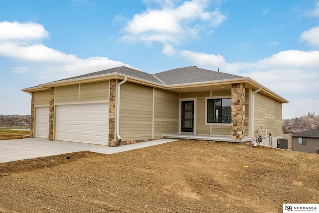 16014 Daniel St, Bennington, NE 68007 - view of front of house featuring a garage, stone siding, concrete driveway, a porch, and central air condition unit
