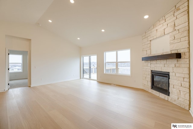 16014 Daniel St, Bennington, NE 68007 - unfurnished living room with vaulted ceiling, a stone fireplace, a wealth of natural light, and light wood finished floors