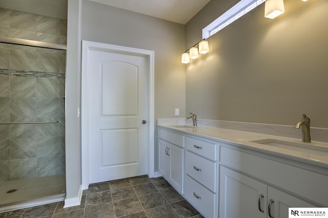 bathroom with a sink, a tile shower, and double vanity