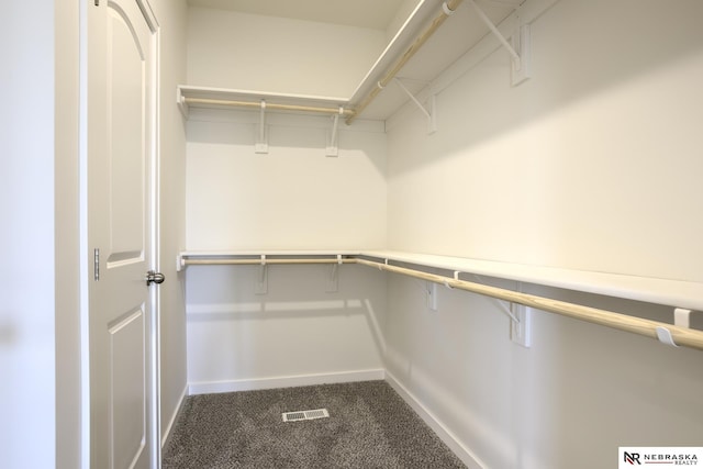 spacious closet featuring visible vents and dark colored carpet