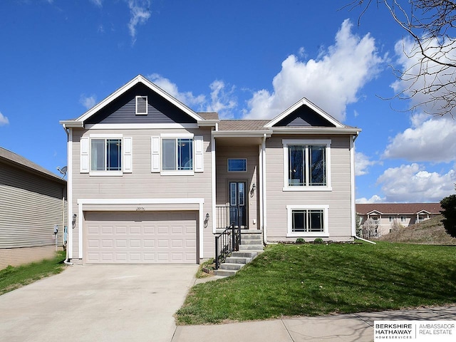 bi-level home with an attached garage, concrete driveway, and a front lawn