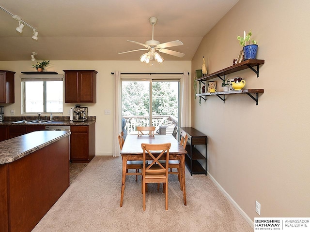 dining space featuring track lighting, light carpet, baseboards, ceiling fan, and vaulted ceiling