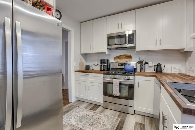 kitchen with stainless steel appliances, wood counters, light wood-style flooring, and tasteful backsplash
