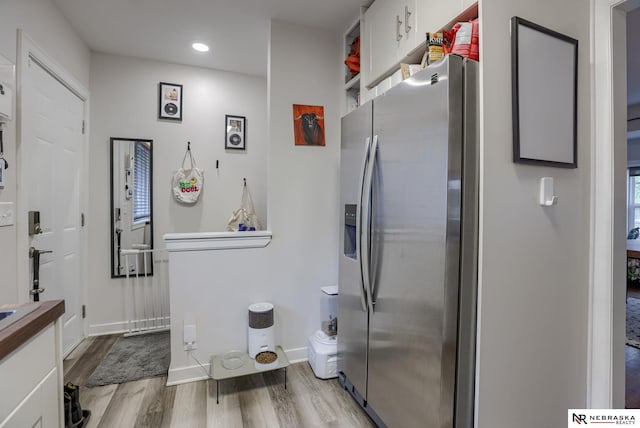 kitchen with white cabinets, recessed lighting, baseboards, wood finished floors, and stainless steel refrigerator with ice dispenser