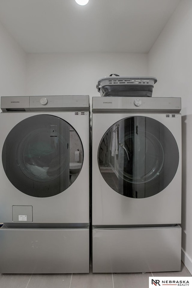 washroom with tile patterned floors, baseboards, laundry area, and washing machine and dryer