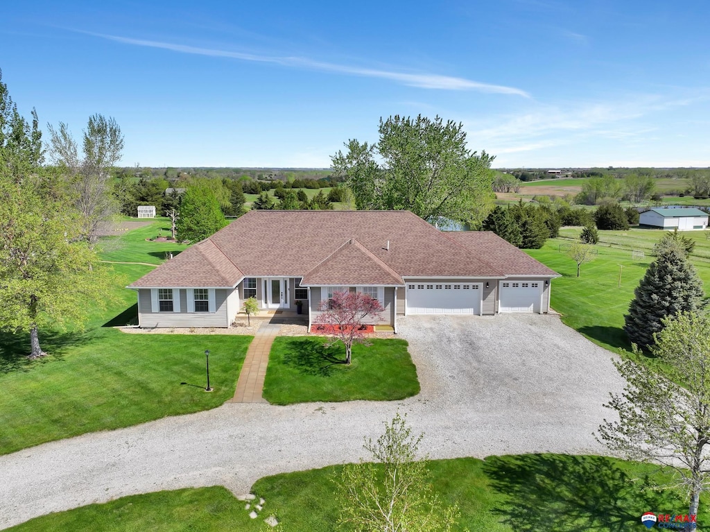 view of front of property featuring a garage, roof with shingles, a front lawn, and gravel driveway