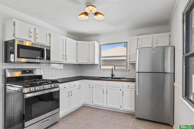 kitchen featuring a sink, dark countertops, stainless steel appliances, and white cabinetry
