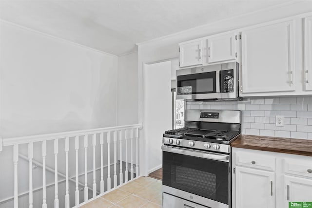 kitchen with backsplash, stainless steel appliances, white cabinetry, and butcher block countertops