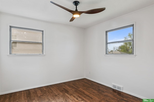 empty room featuring visible vents, ornamental molding, and dark wood finished floors