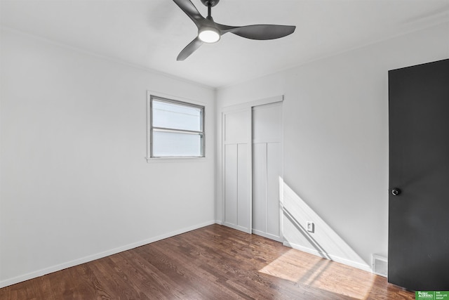 unfurnished bedroom featuring ceiling fan, baseboards, wood finished floors, visible vents, and a closet