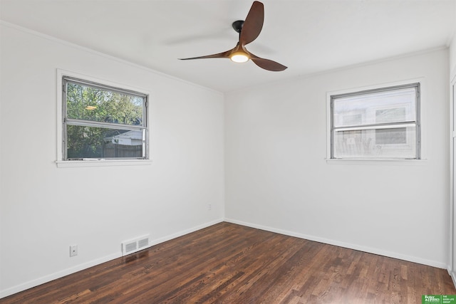 spare room featuring visible vents, ornamental molding, dark wood-style flooring, baseboards, and a ceiling fan