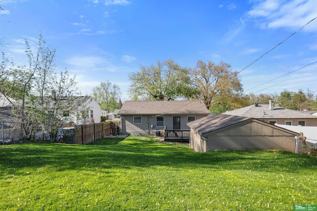 rear view of property with a lawn, fence, and a wooden deck