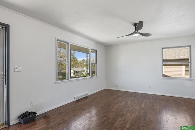 spare room with a ceiling fan, visible vents, wood finished floors, baseboards, and ornamental molding