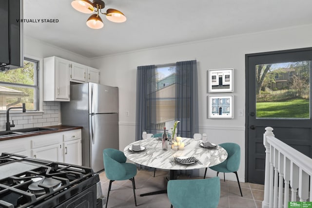 kitchen with backsplash, crown molding, a sink, black gas range oven, and freestanding refrigerator