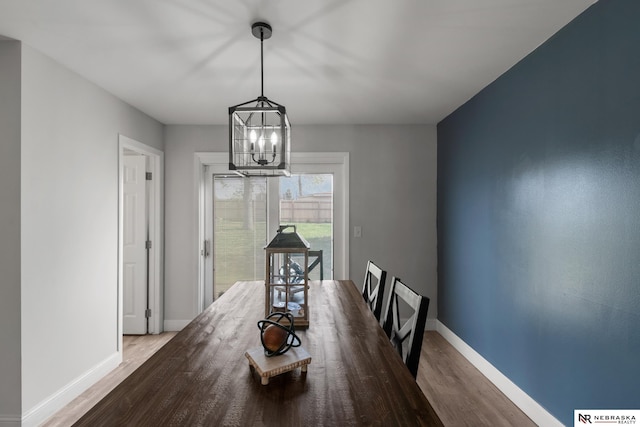 dining area with baseboards, wood finished floors, and a chandelier