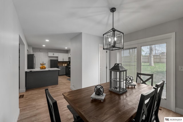 dining area with baseboards, recessed lighting, light wood-style floors, and a chandelier