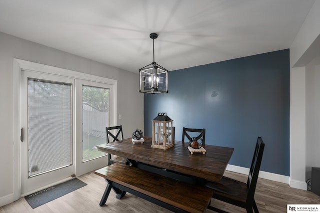 dining area with baseboards, a notable chandelier, and light wood-style floors