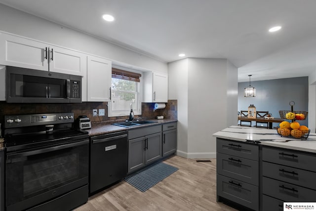 kitchen featuring dishwashing machine, stainless steel microwave, a sink, black / electric stove, and gray cabinetry