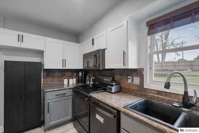 kitchen featuring a sink, tasteful backsplash, black appliances, and white cabinetry