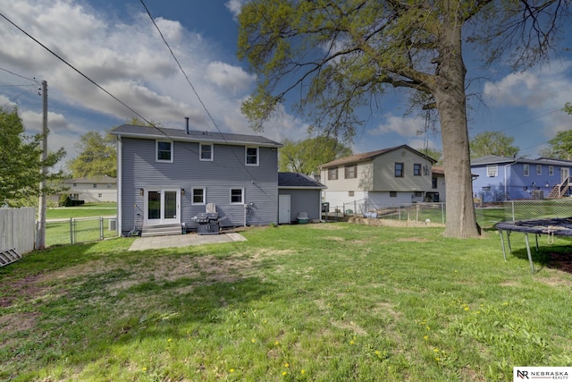 back of property featuring a trampoline, a gate, a fenced backyard, a yard, and entry steps
