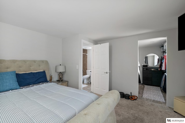 bedroom featuring connected bathroom, light colored carpet, and a walk in closet