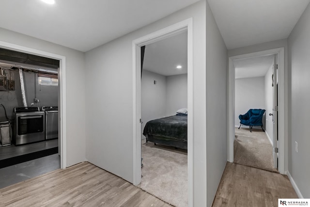 hall with washing machine and dryer and wood finished floors