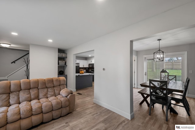 living room with light wood-style floors, recessed lighting, baseboards, and a chandelier