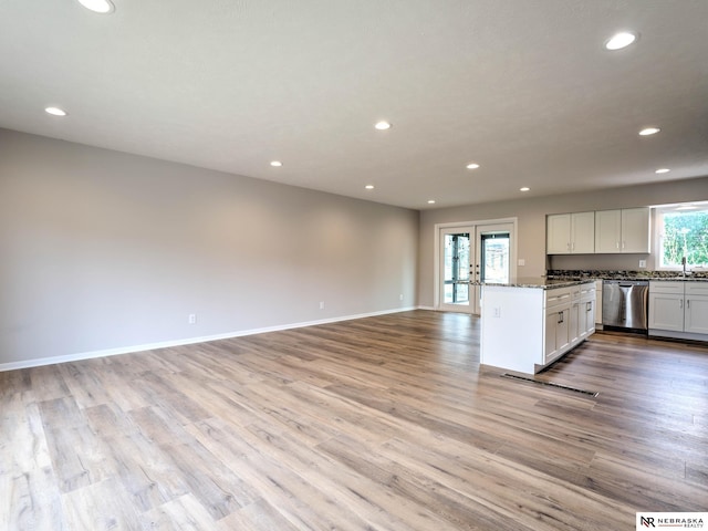 kitchen with stainless steel dishwasher, recessed lighting, dark stone counters, and white cabinetry