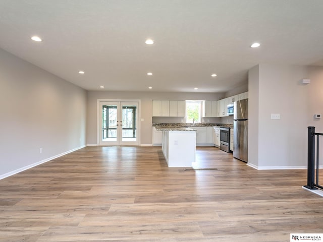 kitchen with open floor plan, recessed lighting, light wood-type flooring, white cabinets, and stainless steel appliances