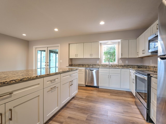 kitchen featuring white cabinetry, a sink, appliances with stainless steel finishes, and light stone counters