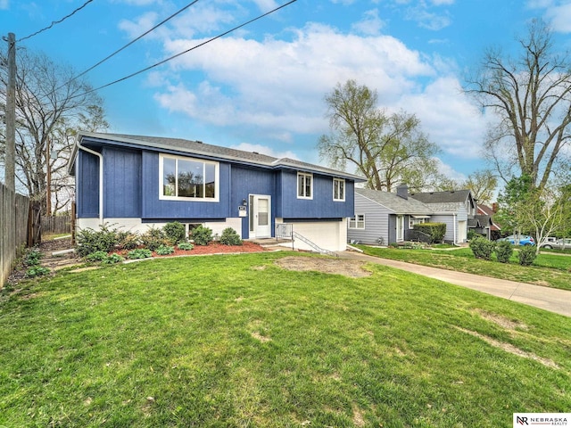 bi-level home featuring concrete driveway, fence, a front yard, and a garage