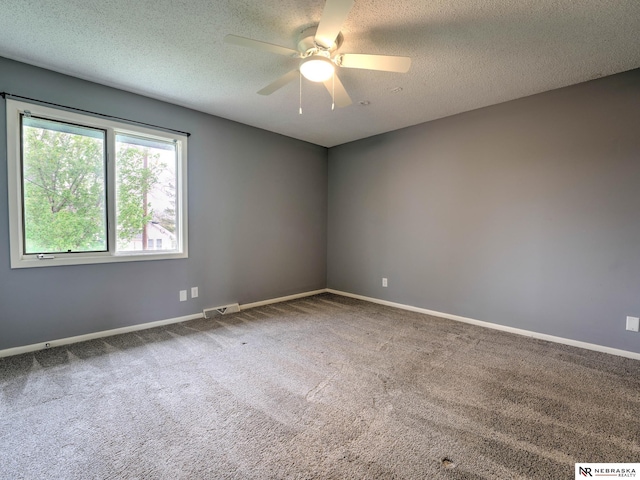 carpeted spare room with baseboards, a ceiling fan, a textured ceiling, and visible vents