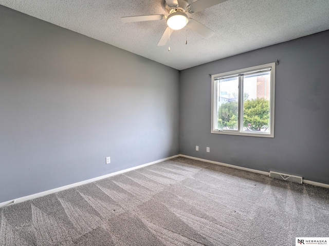 carpeted spare room with baseboards, a ceiling fan, a textured ceiling, and visible vents