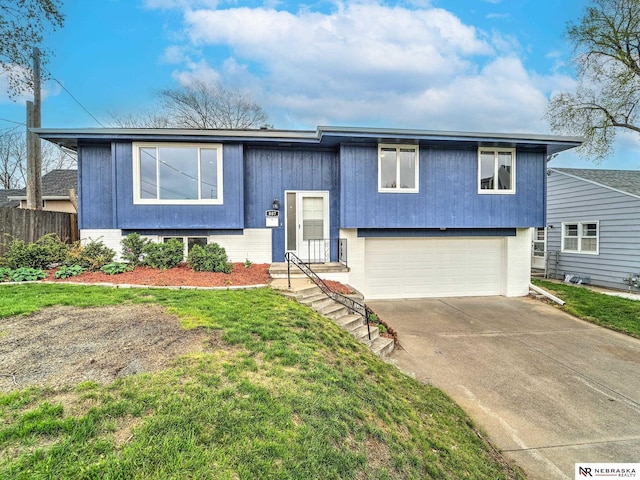 bi-level home with a garage, brick siding, fence, a front lawn, and concrete driveway