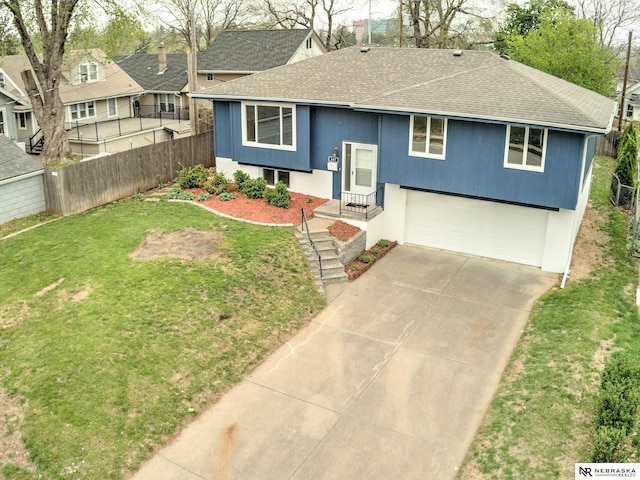 raised ranch with fence, a shingled roof, a garage, a front yard, and driveway
