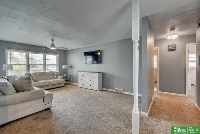 living room featuring carpet floors, a ceiling fan, baseboards, and visible vents