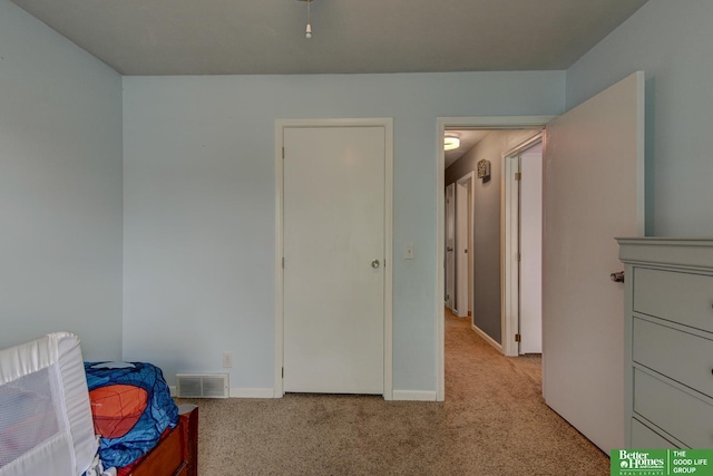 unfurnished bedroom with baseboards, light carpet, and visible vents